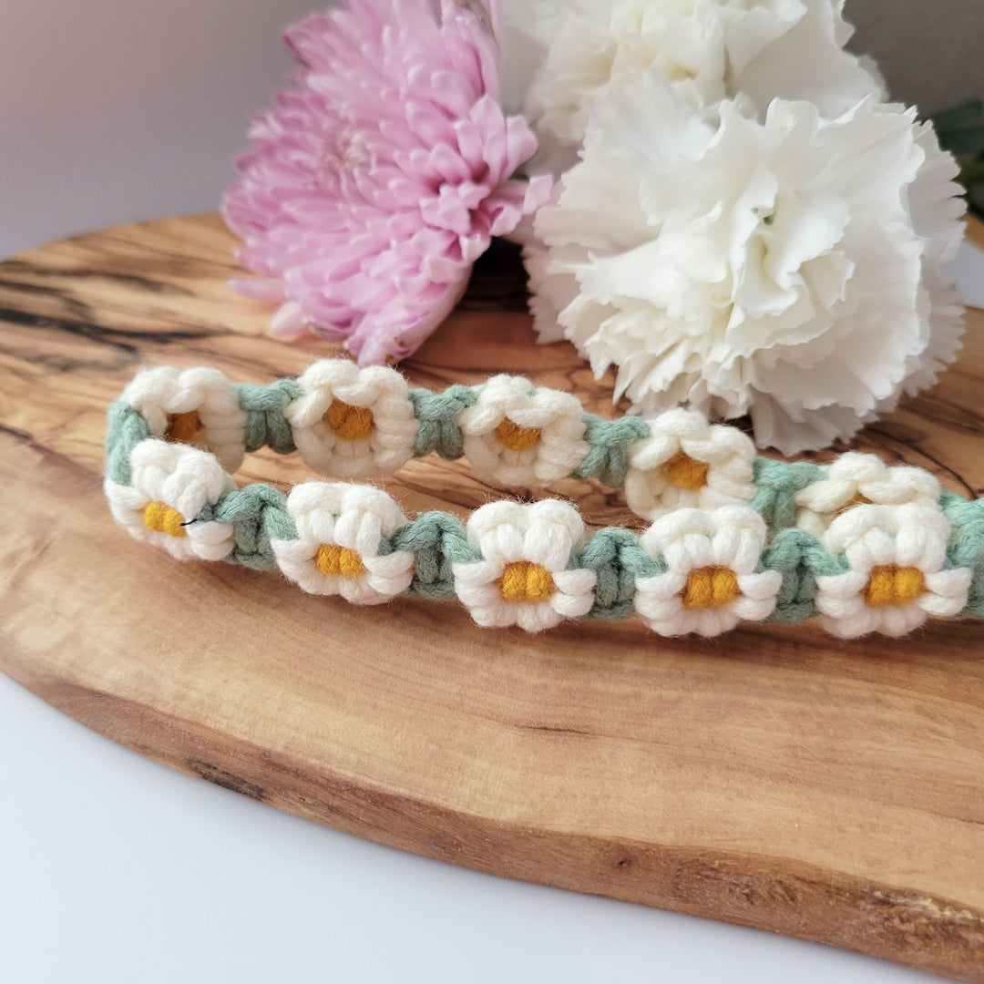 Green and White Flower Macrame Wristlet Keychain with gold clip, laying on a piece of wood