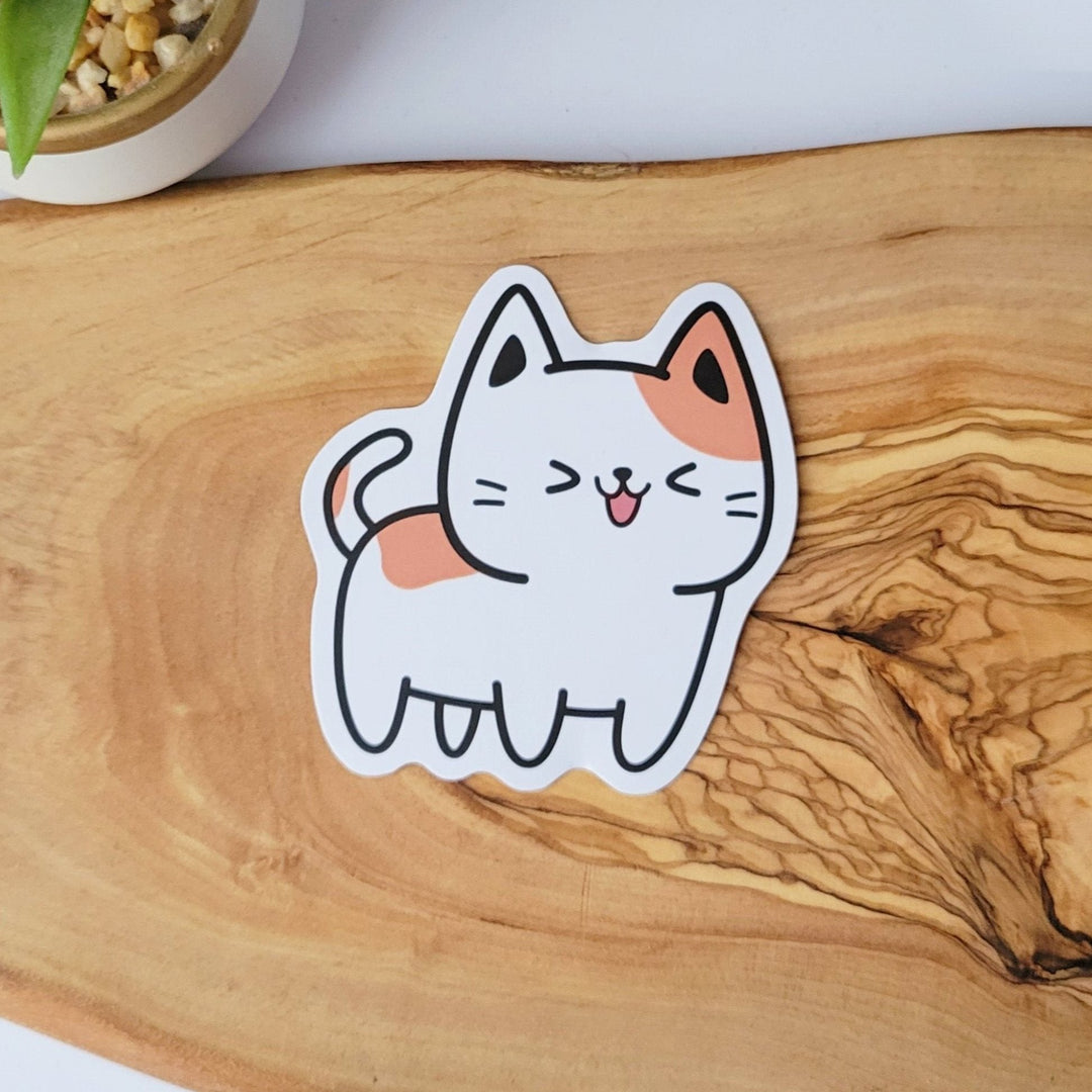 a white cat shaped sticker with a happy laughing face