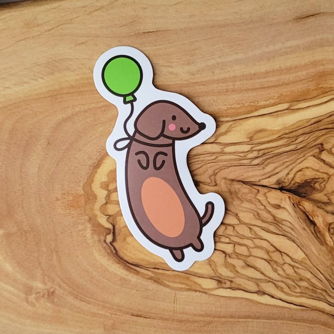 a brown dog with a green balloon tied to it's neck, with a bow