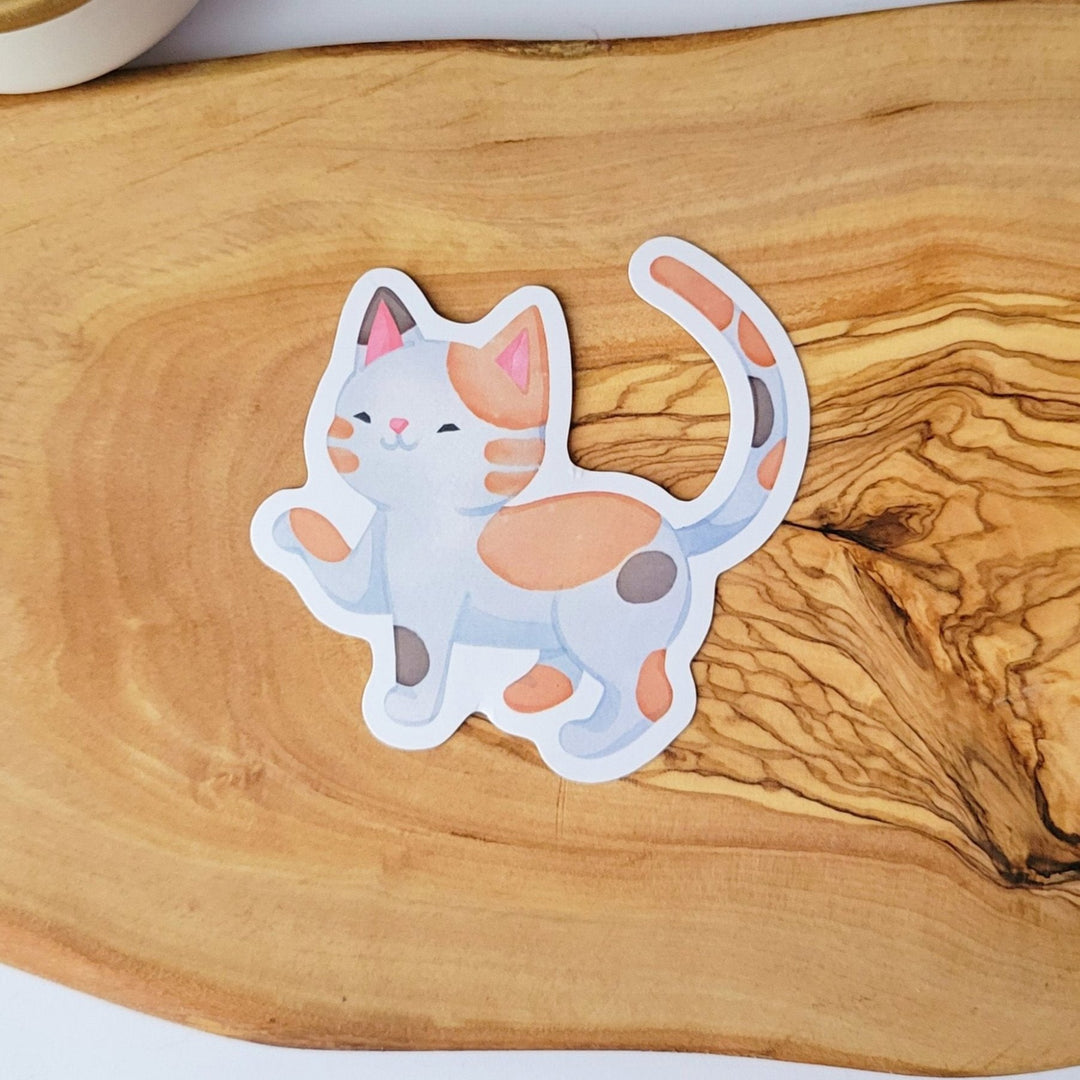 a sticker of a cute watercolor white style cat with tan and gray patches walking.
