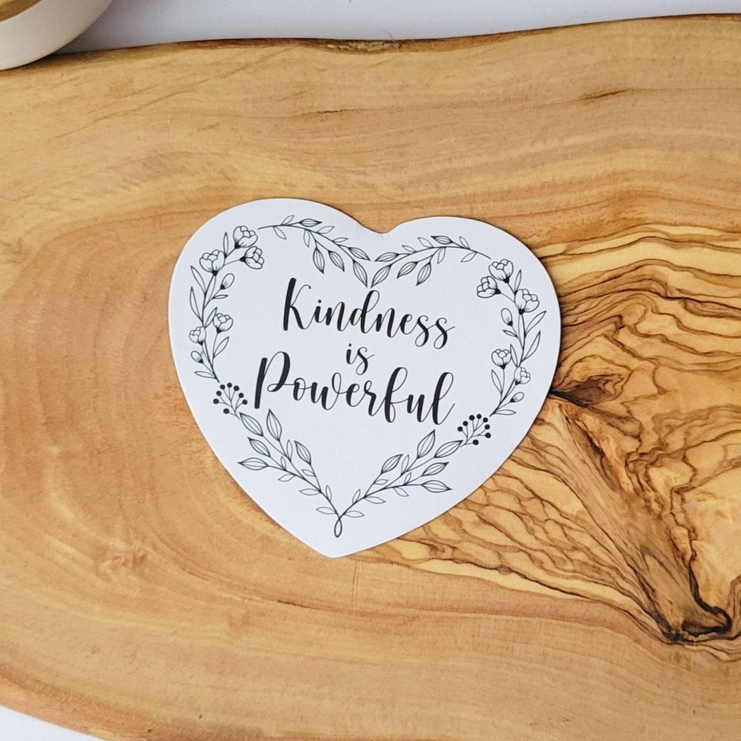 Heart shaped white sticker, with Kindness is Powerful in black cursive writing, and a heart shaped wreath with leaves and flowers