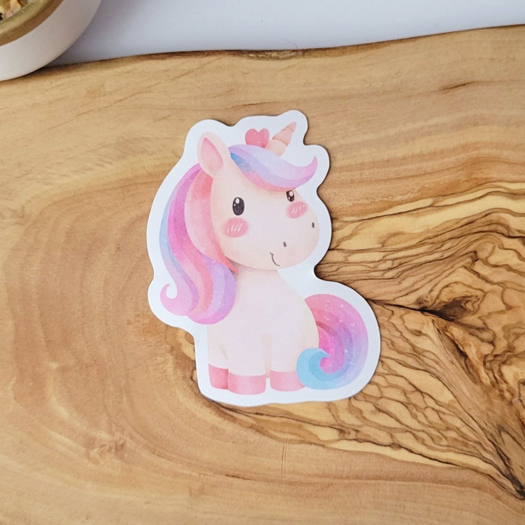 A smiling tan watercolor style unicorn, with rainbow hair.