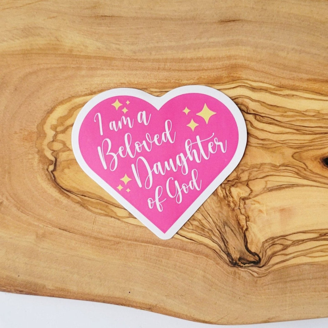 A sticker of a pink heart with yellow stars, with the words "I am a Beloved Daughter of God"