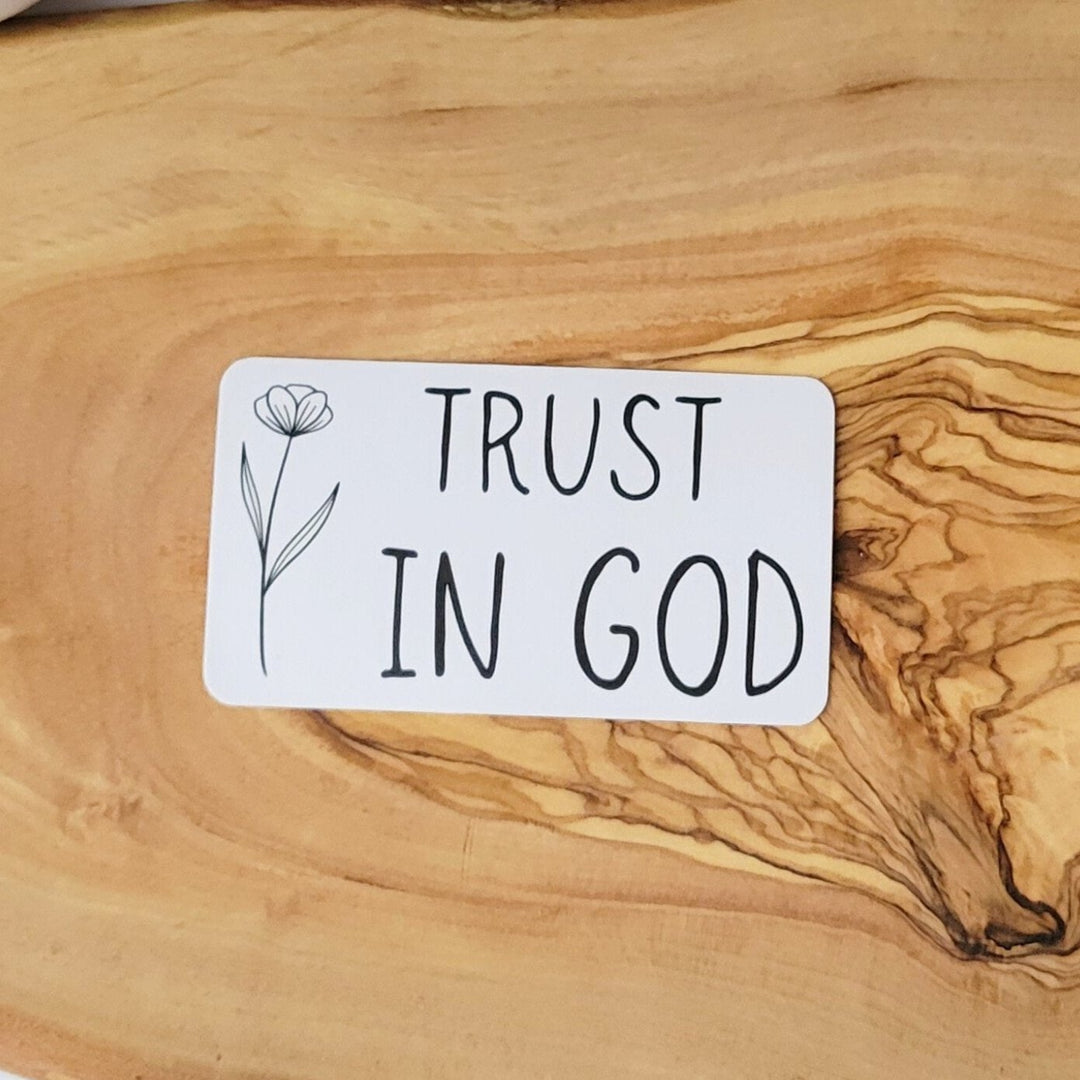 A white rectangle sticker, with Trust in God and a single flower