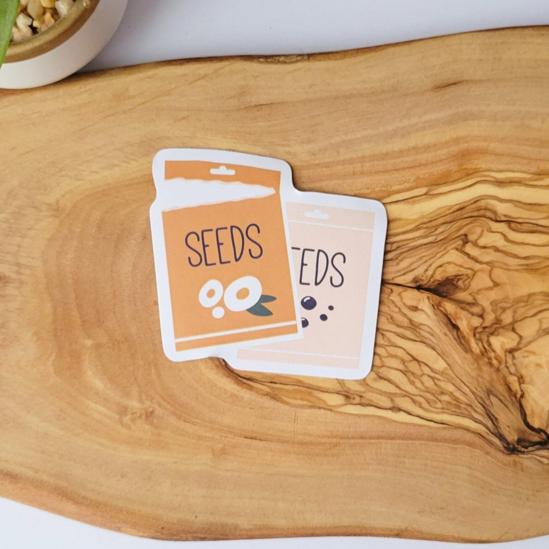 two packets of tan and cream colored garden seeds, one package is torn open
