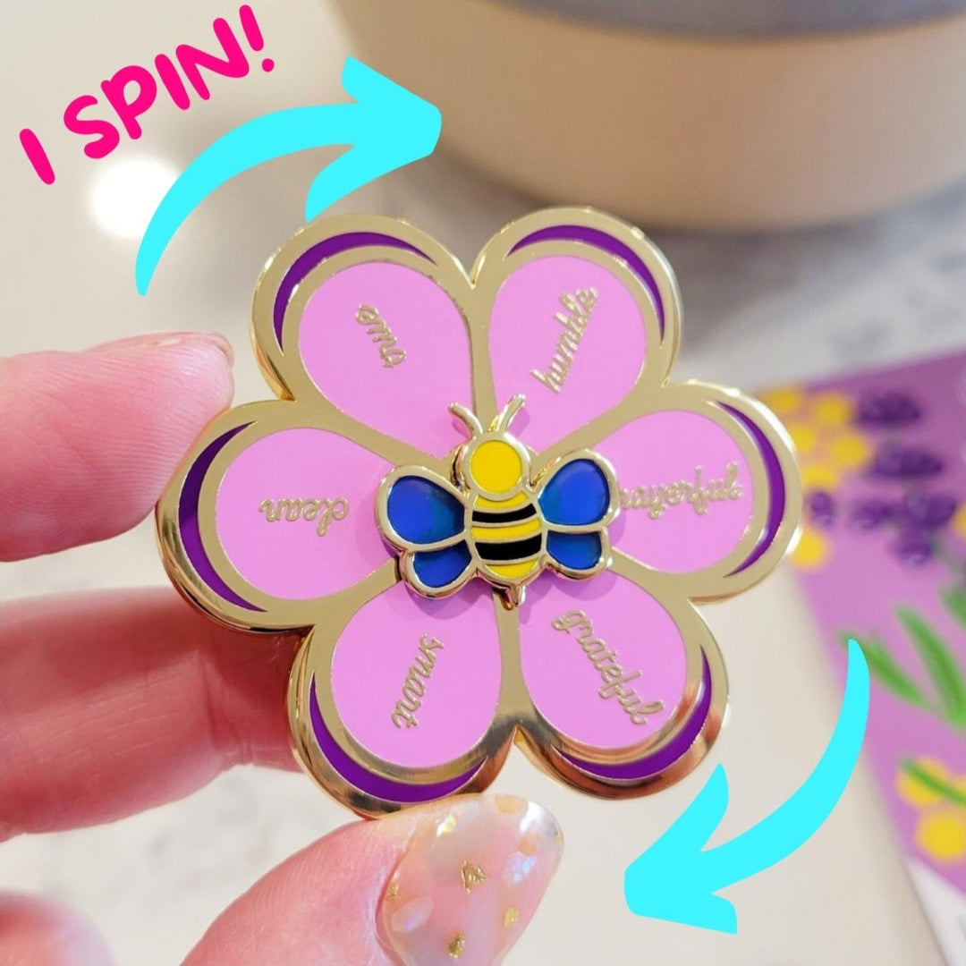 a purple flower enamel pin, with a small yellow bee, with petals that move