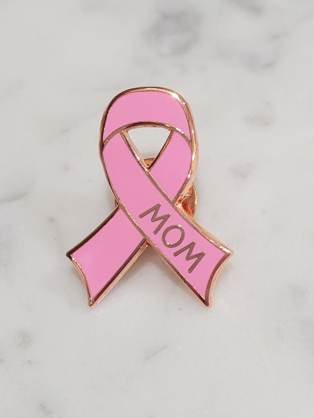 close up of the words mom on a breast cancer enamel pin