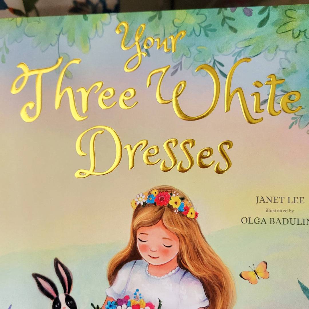 Book cover of 'Your Three White Dresses' with a girl in a white dress holding flowers, surrounded by butterflies and flowers.